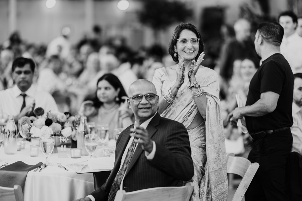 Bride's parents clap and smiles during wedding reception at Garfield Park Conservatory, surrounded by seated guests at round tables