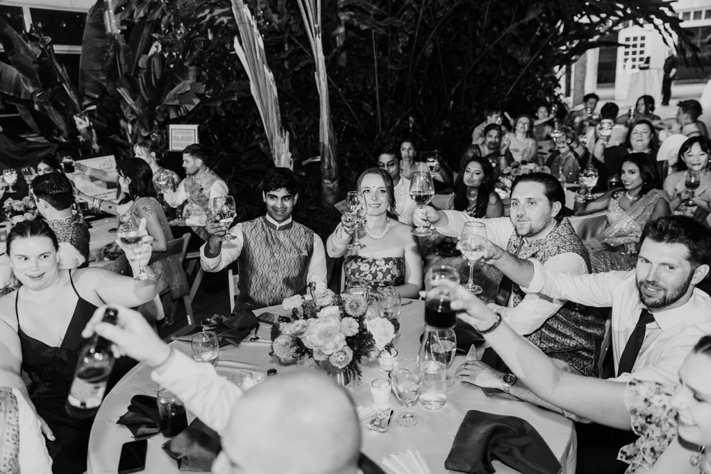 Black and white photo of guests at a Chicago Indian wedding reception raising their glasses in a toast