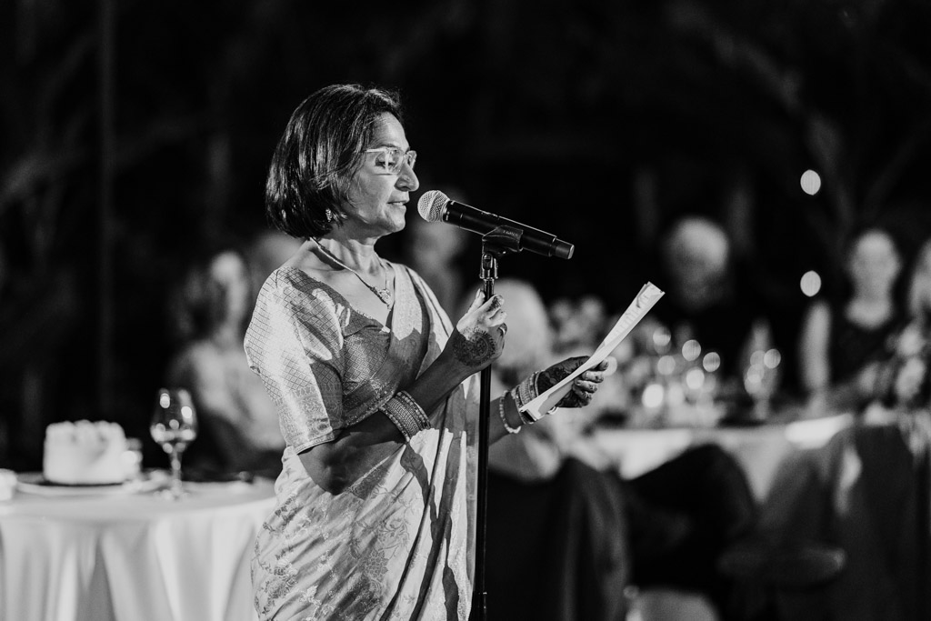 Mother of the bride gives speech during Chicago Indian wedding reception with seated guests in the background