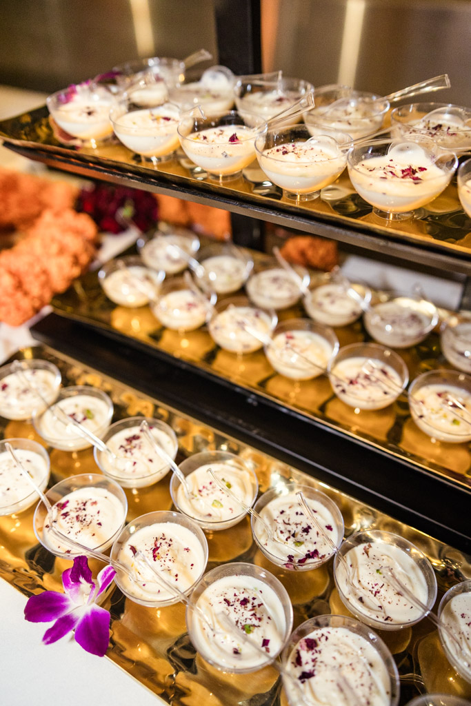Mini dessert cups with herbs on gold trays, next to a purple orchid flower for Chicago Indian wedding reception