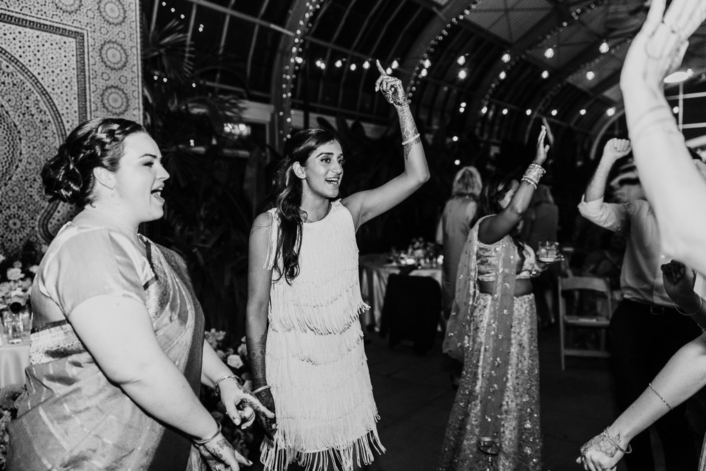 Black and white photo of bride and guests dancing during Indian wedding reception at Garfield Park Conservatory