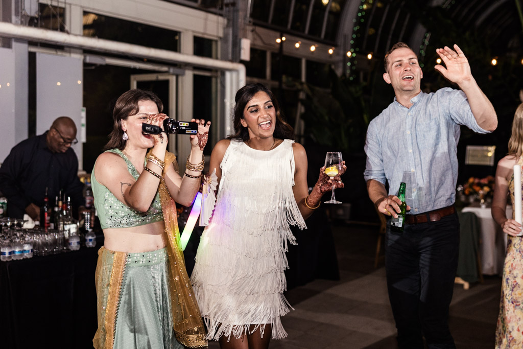 Bride and two guests laugh and dance at a lively Chicago Indian wedding reception