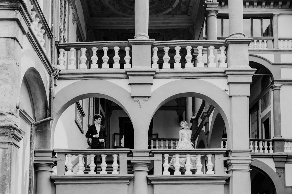 Editorial style Italy engagement photo in Tuscany at Orto Botanico in Lucca with man and woman standing on historic balcony
