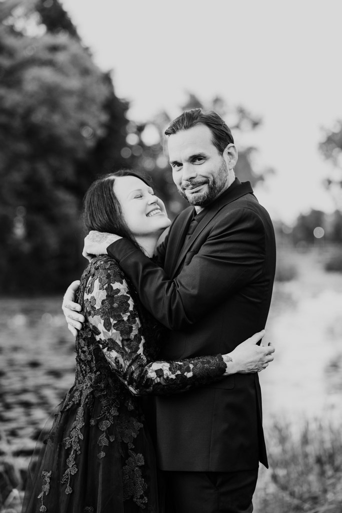 A couple in formal attire embracing outdoors.
